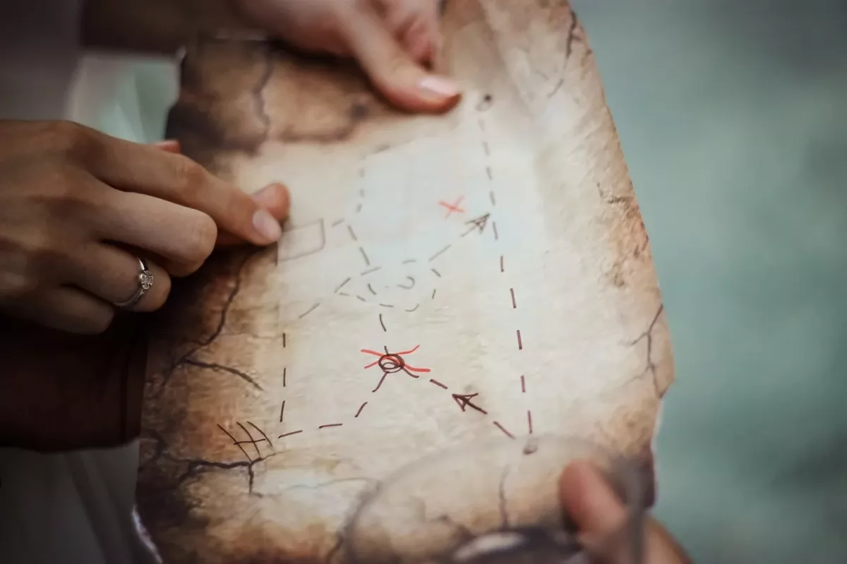 Carte d'explorateur: envie d'explorer en solo Main tenant une carte d’explorateur avec un obstacle sur le chemin, représentant les blocages liés au refus et à la phobie scolaire. Boite à outil