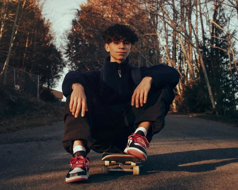 Adolescent assis sur un skateboard, regard déterminé : il reprend confiance, clarifie son orientation et avance avec l’accompagnement de Cap Toi M’aime à Genève (phobie/refus scolaire, décrochage).
