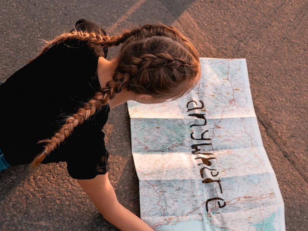 Retrouver sa liberté et son chemin Jeune fille regardant une carte 'Anywhere', symbolisant le potentiel et la liberté retrouvés grâce à l'accompagnement contre le refus scolaire